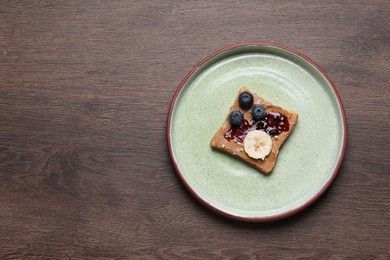 Photo of Toast with tasty nut butter, jam, blueberries, nuts and banana on wooden table, top view. Space for text