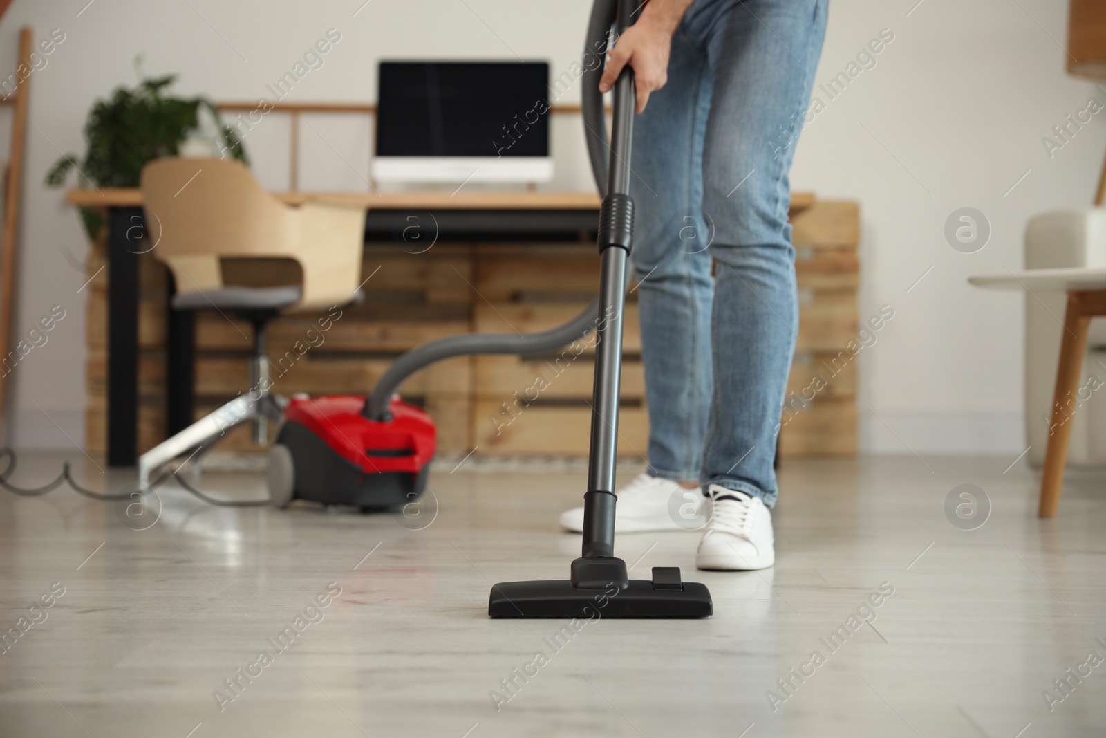 Photo of Young man using vacuum cleaner at home, closeup