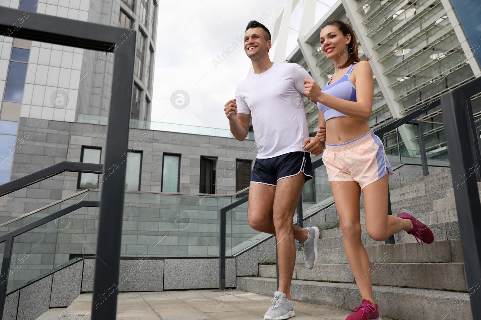 Photo of Man and woman in fitness clothes running downstairs outdoors