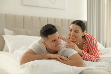 Happy couple in pyjamas lying on bed at home