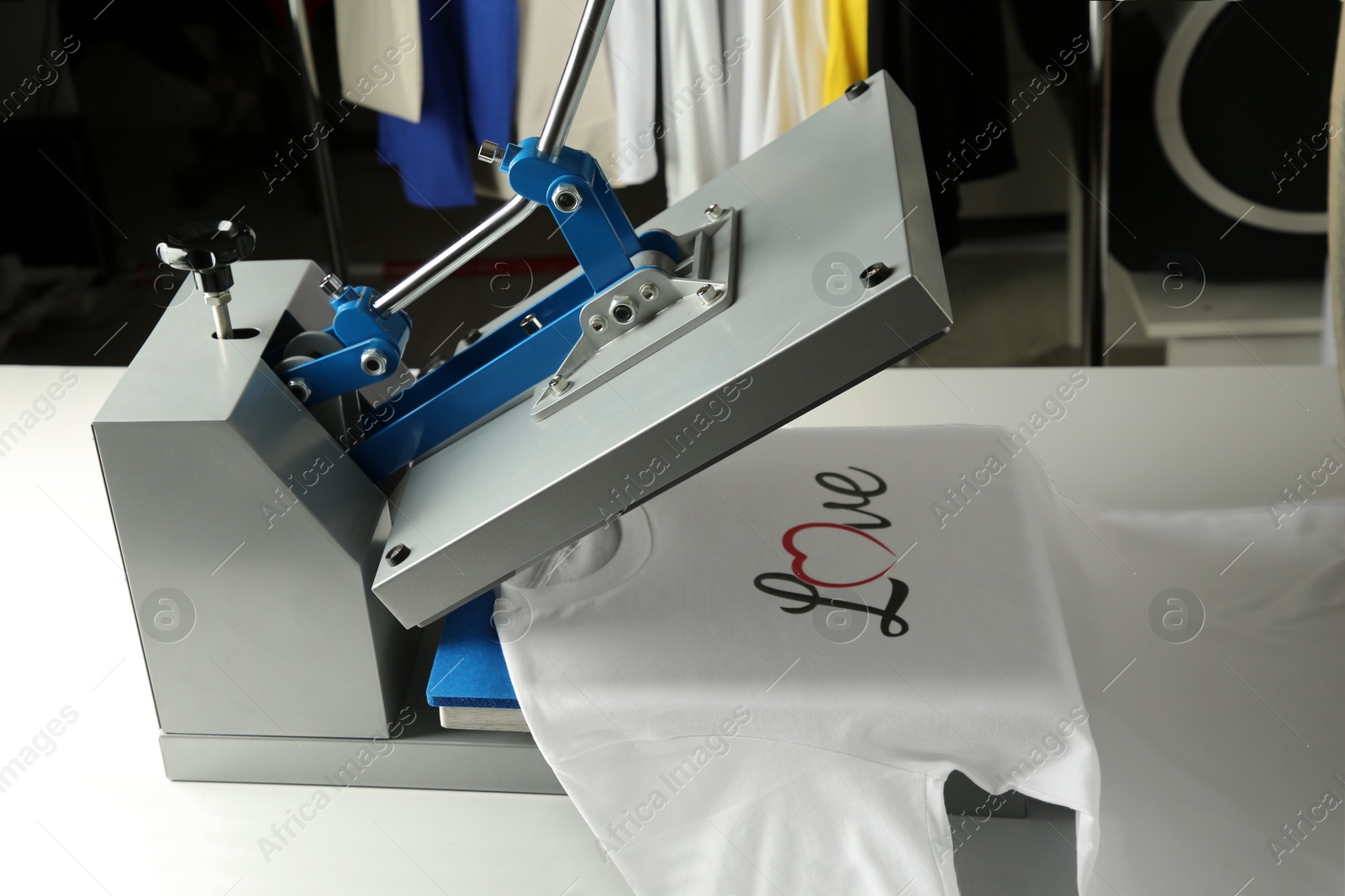 Photo of Printing logo. Heat press with t-shirt on white table