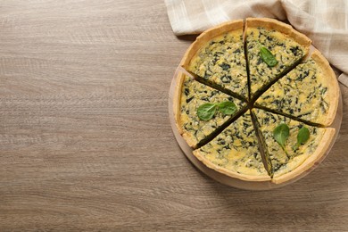 Photo of Cut delicious spinach pie on wooden table, top view. Space for text