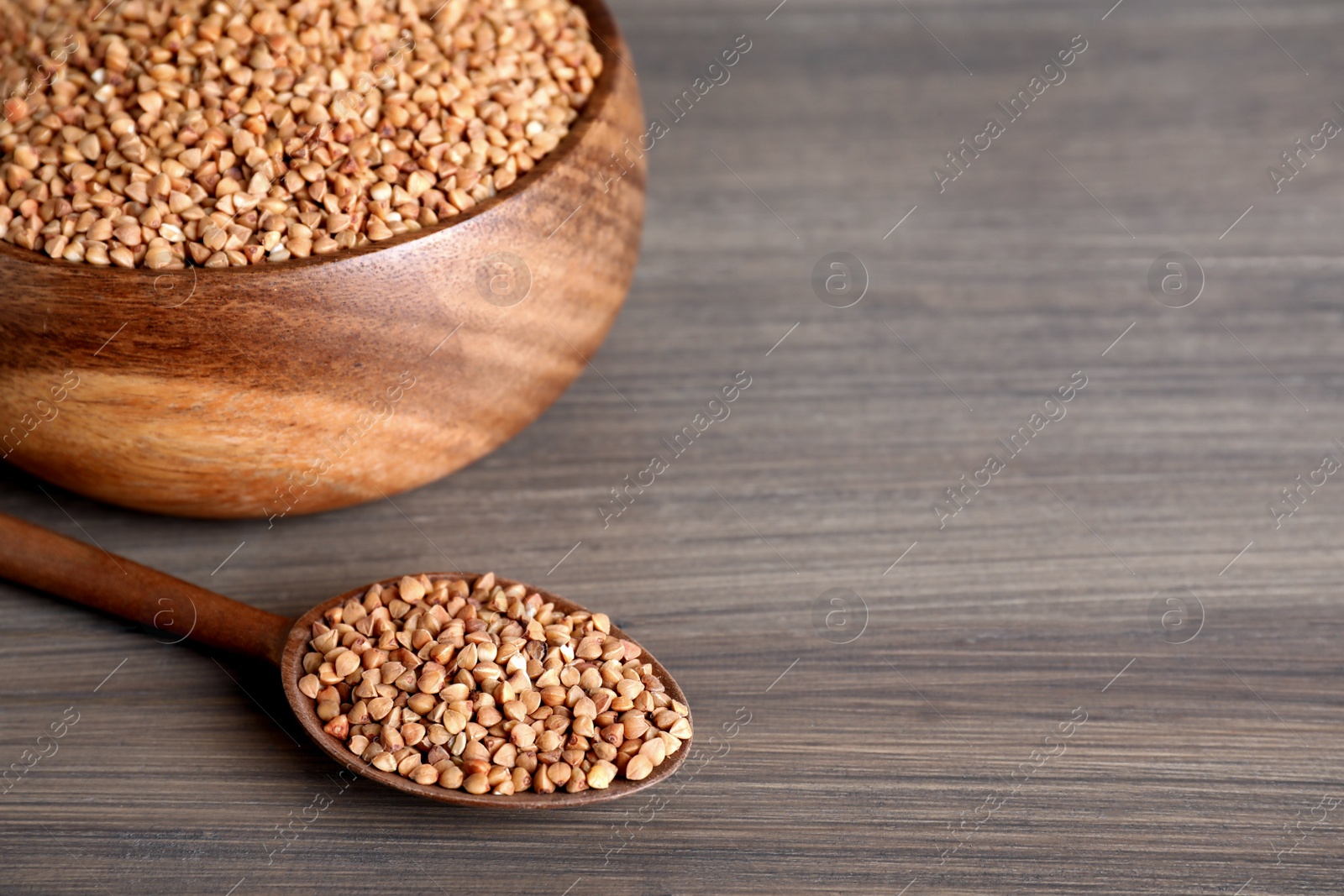 Photo of Uncooked buckwheat on wooden table. Space for text