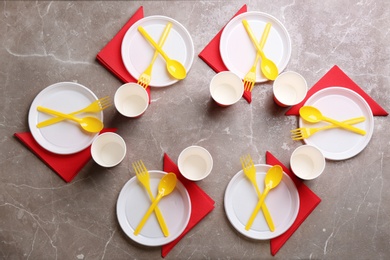 Composition with plastic dishware on grey background, flat lay. Picnic table setting