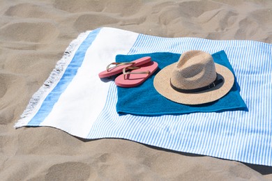 Photo of BLue towels, flip flops and straw hat on sandy beach