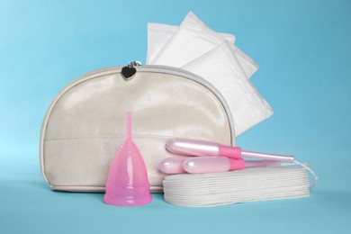 Photo of Bag with menstrual pads and other hygiene products on light blue background