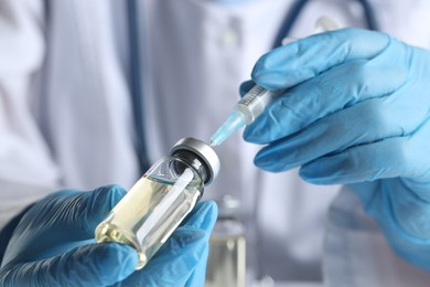 Photo of Doctor filling syringe with medication from glass vial, closeup