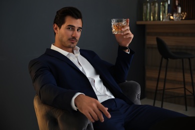 Photo of Young man with glass of whiskey in bar
