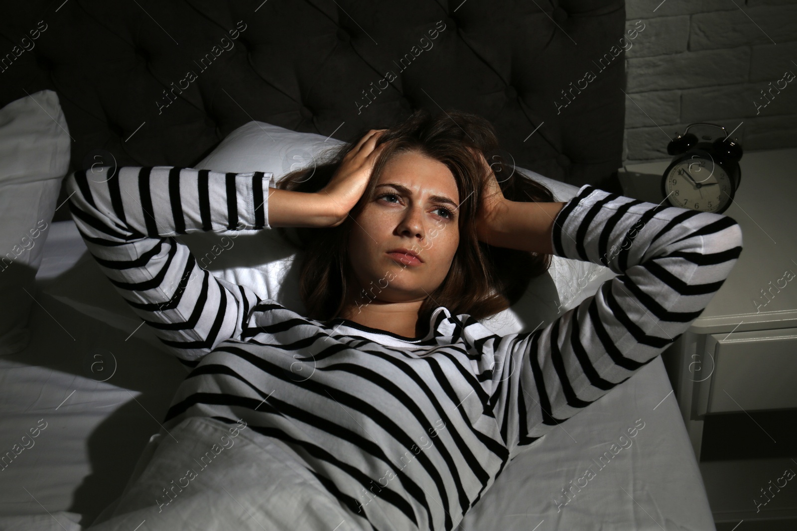 Photo of Young woman suffering from insomnia in bed at home