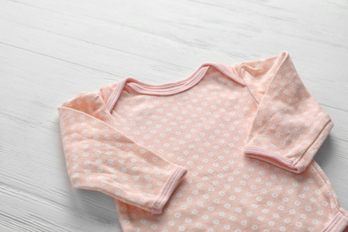 Photo of Child's bodysuit on white wooden table, closeup