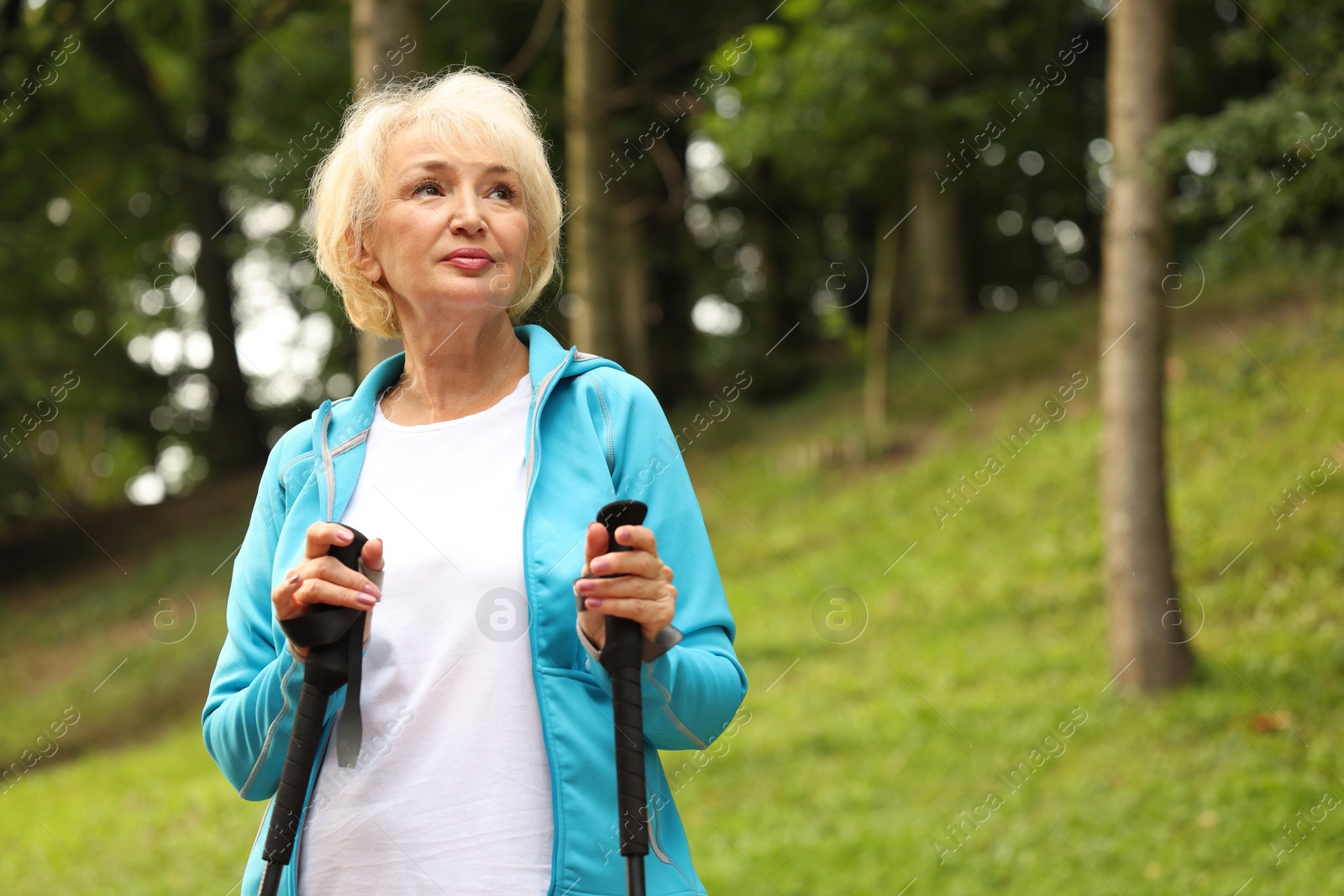 Photo of Senior woman with Nordic walking poles outdoors, space for text