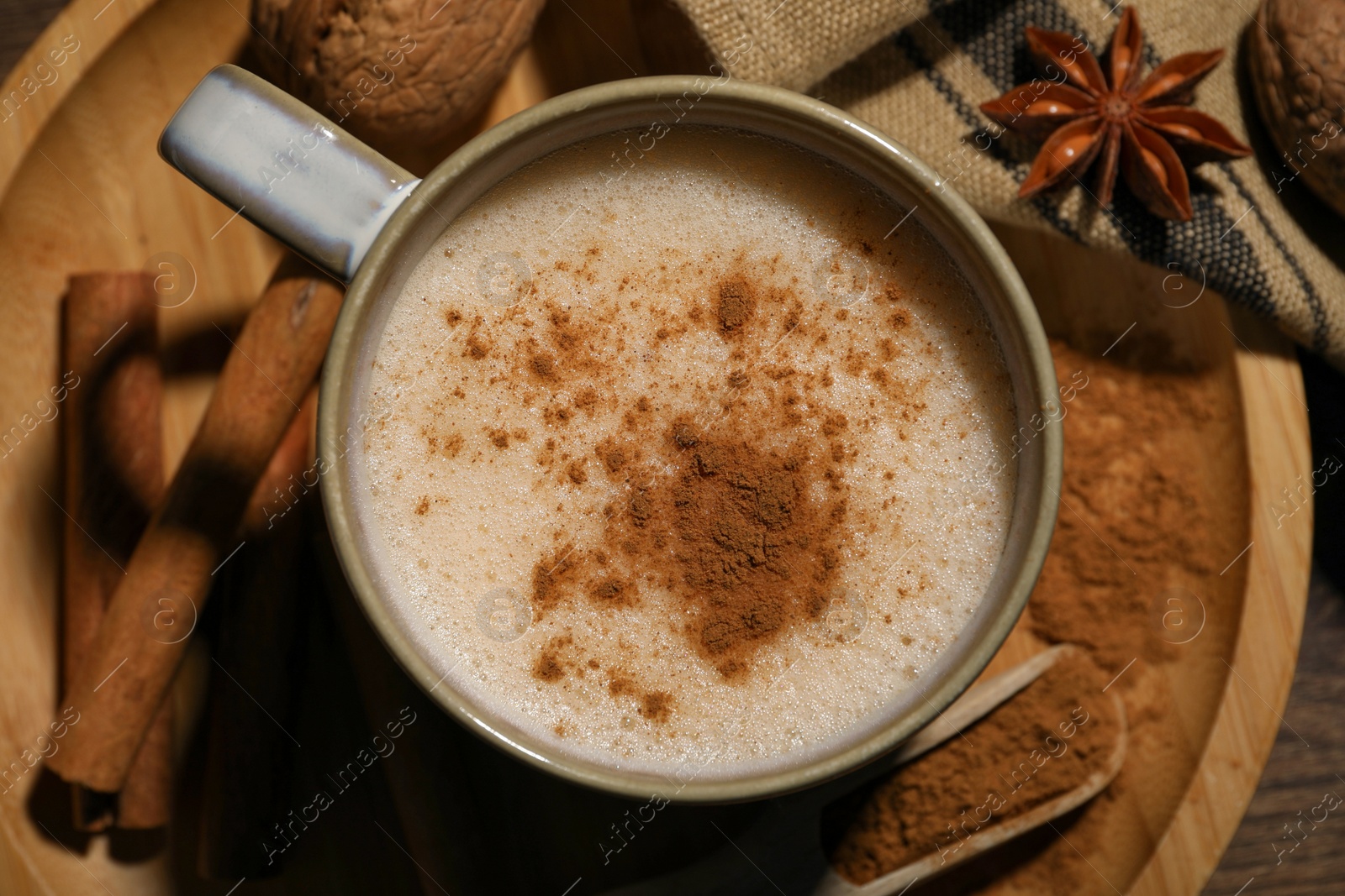 Photo of Cup of delicious eggnog with spices on wooden table, top view