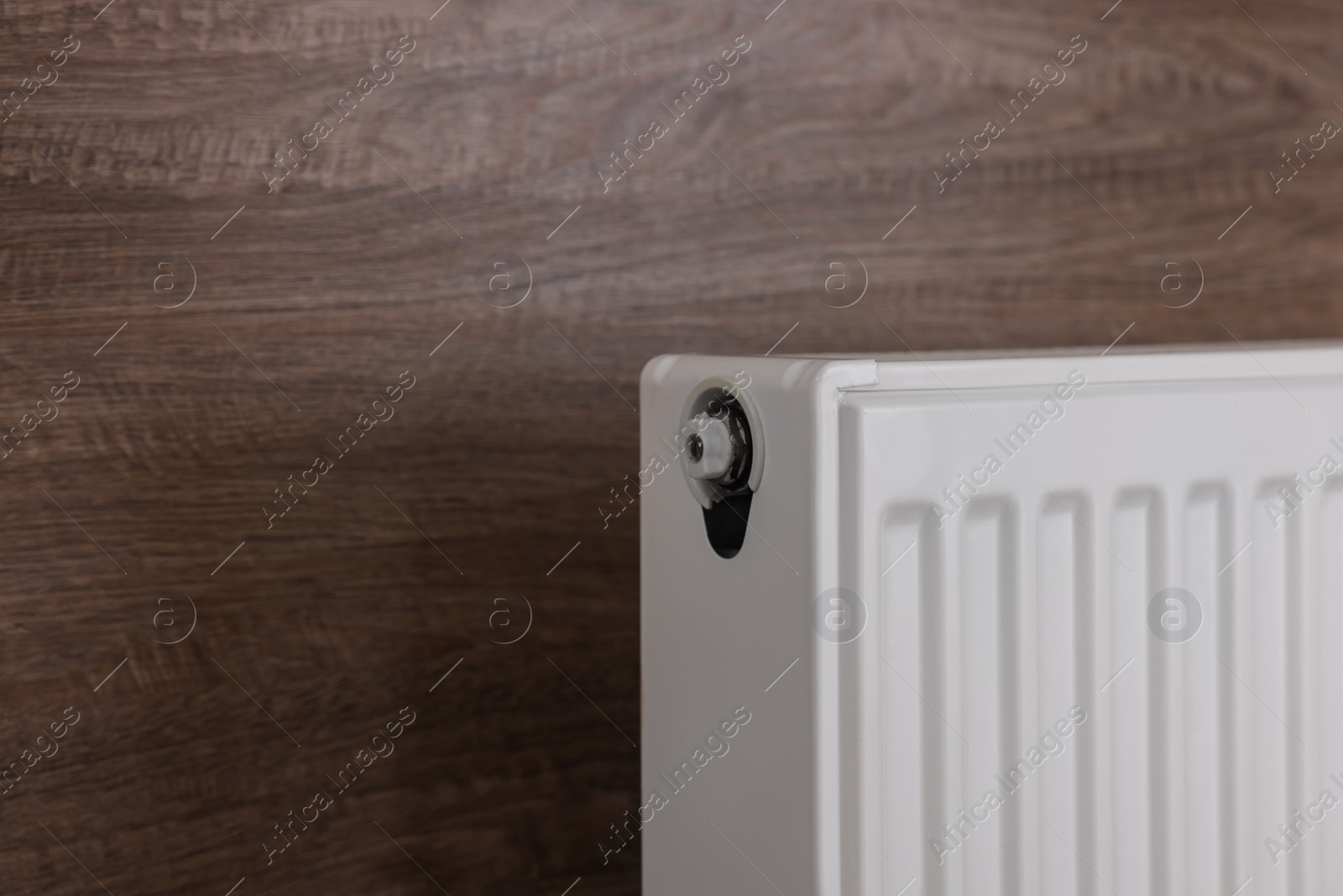 Photo of Modern radiator on wooden wall, closeup with space for text. Central heating system