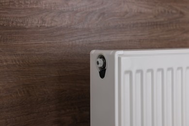 Photo of Modern radiator on wooden wall, closeup with space for text. Central heating system