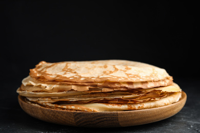 Stack of fresh thin pancakes on black table