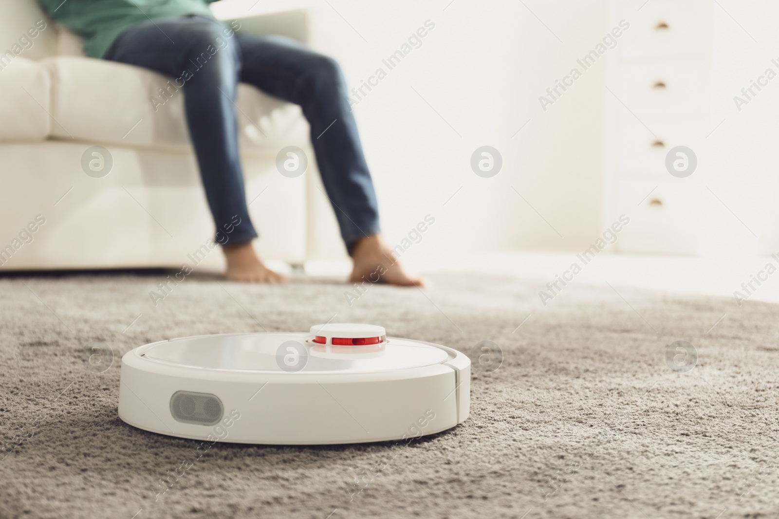 Photo of Man resting while robotic vacuum cleaner doing his work at home