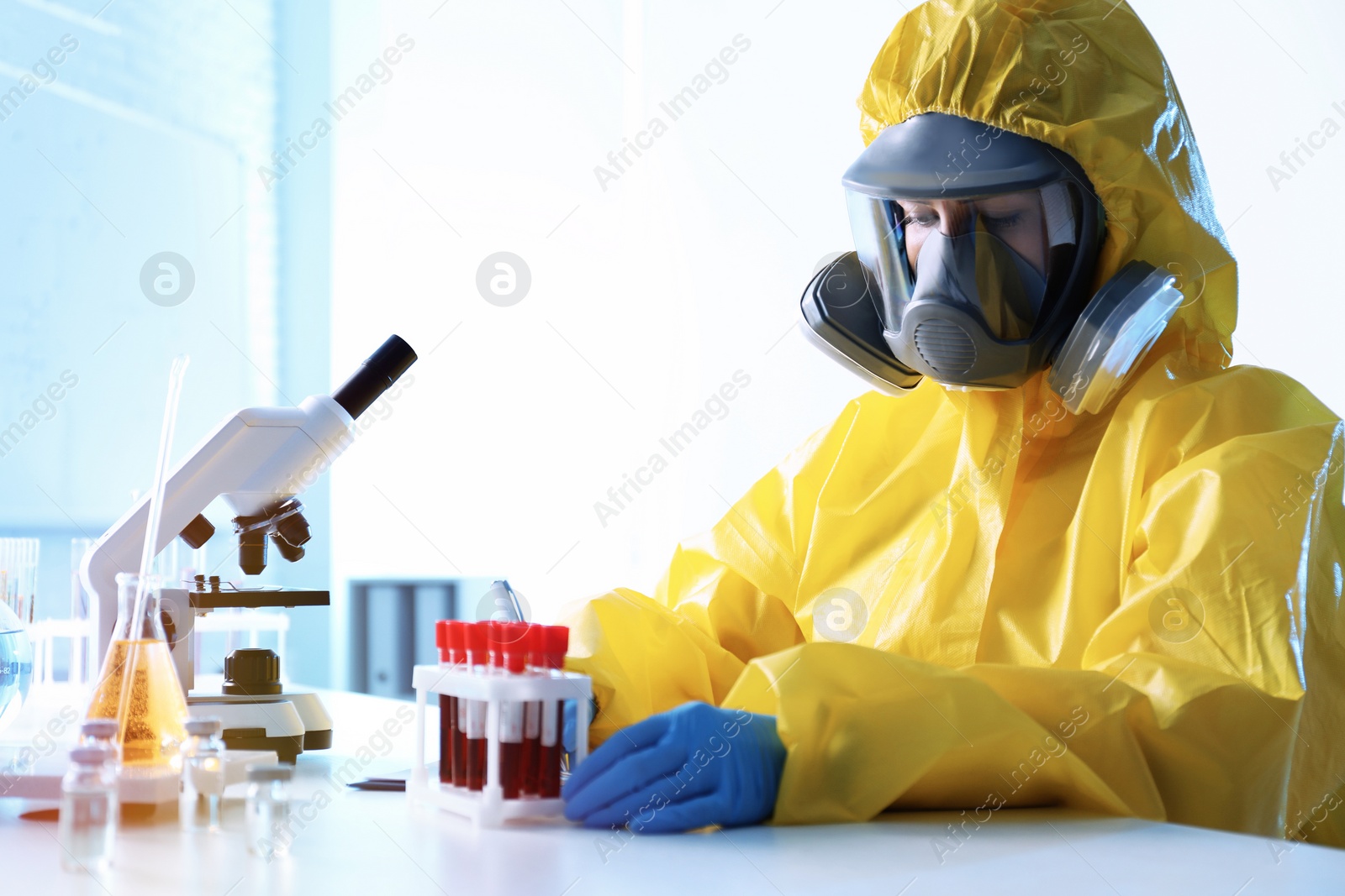 Photo of Scientist in chemical protective suit working with blood samples at laboratory. Virus research