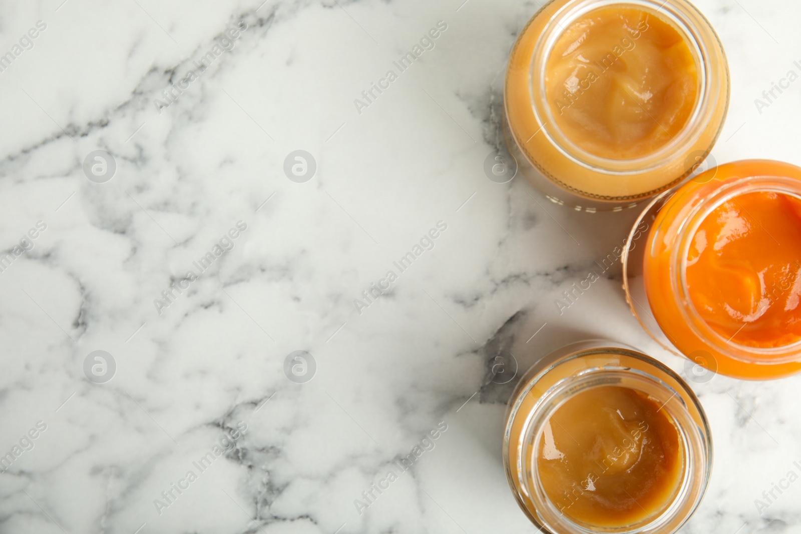 Photo of Healthy baby food in jars on marble table, flat lay. Space for text