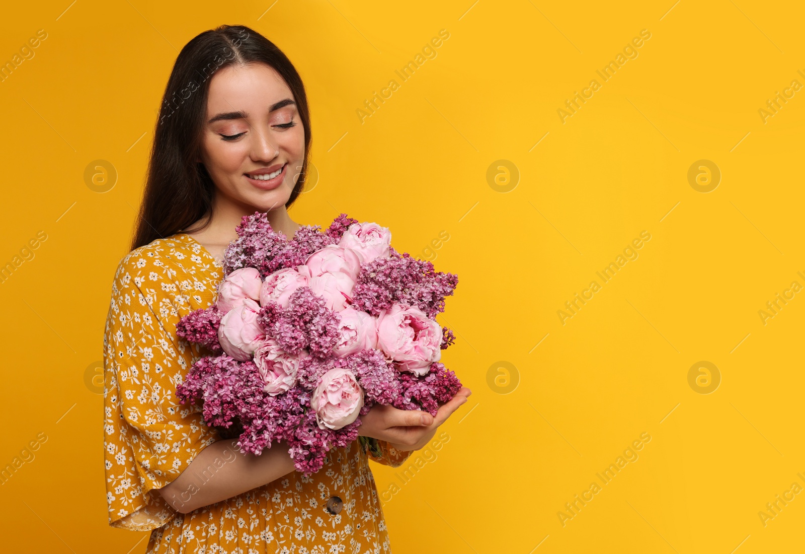 Photo of Beautiful woman with bouquet of spring flowers on yellow background, space for text