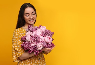 Beautiful woman with bouquet of spring flowers on yellow background, space for text