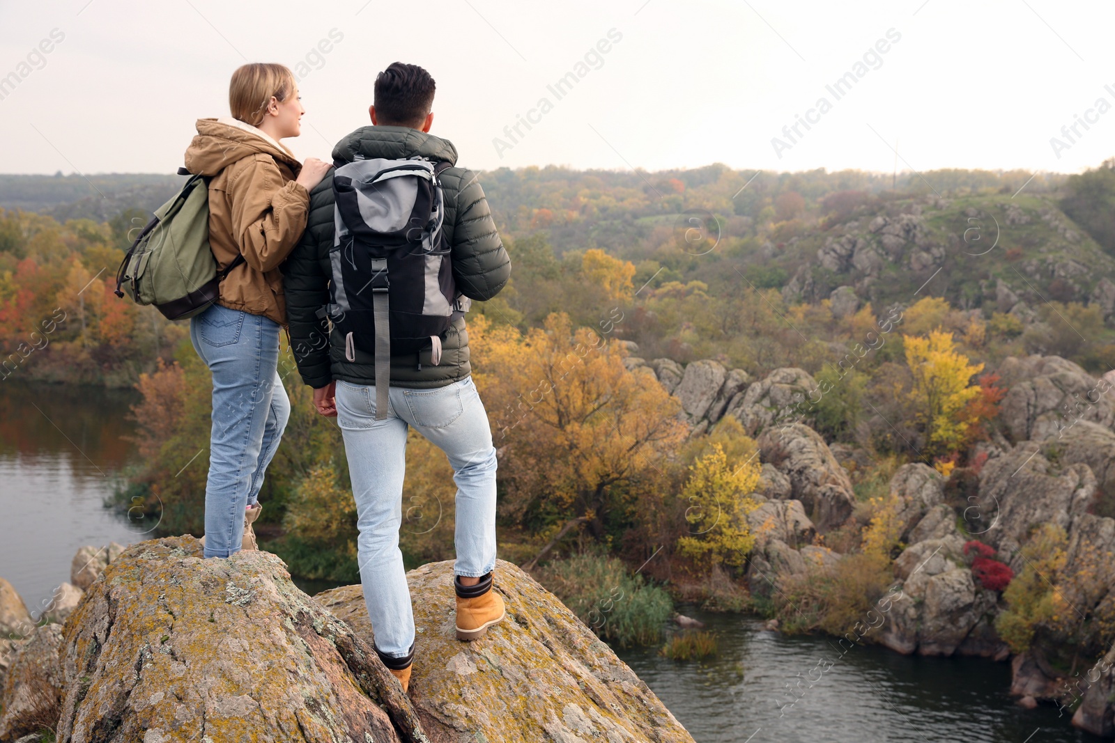 Photo of Couple of hikers with travel backpacks enjoying beautiful view near mountain river