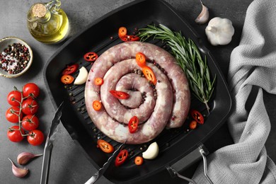 Photo of Pan with raw homemade sausage, spices, oil and tomatoes on grey table, flat lay