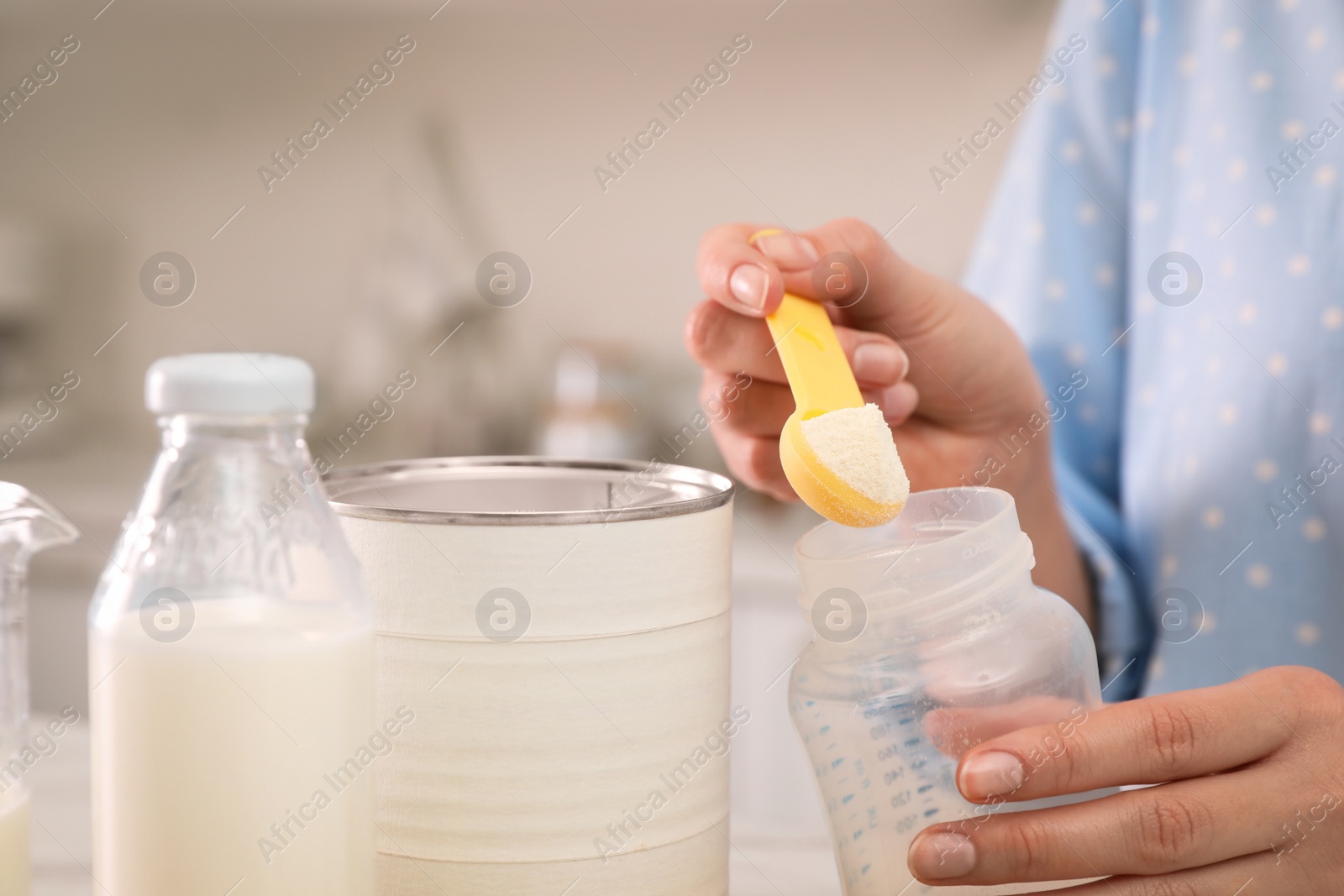 Photo of Woman preparing infant formula indoors, closeup. Baby milk