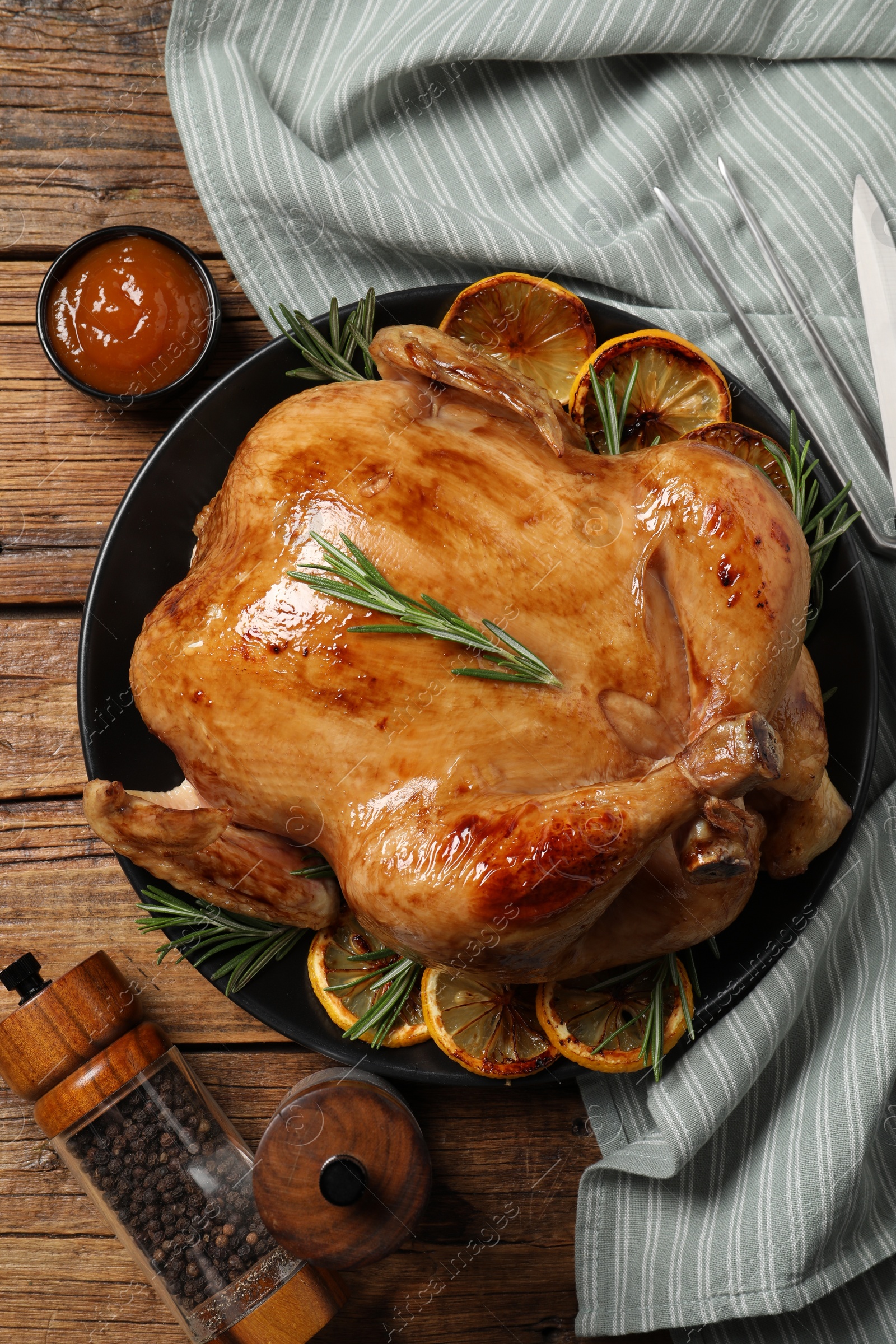 Photo of Tasty roasted chicken with rosemary and lemon served on wooden table, flat lay