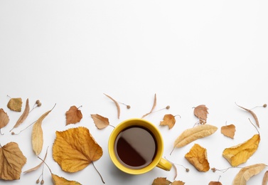 Photo of Cup of hot drink and autumn leaves on white background, flat lay with space for text. Cozy atmosphere