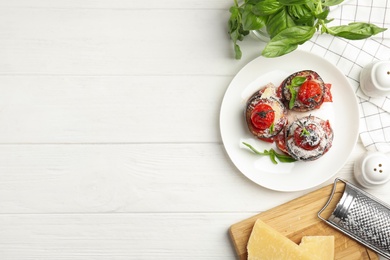 Photo of Baked eggplant with tomatoes, cheese and basil served on white wooden table, flat lay. Space for text