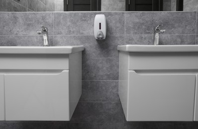 Public toilet interior with stylish white sinks and grey tiles