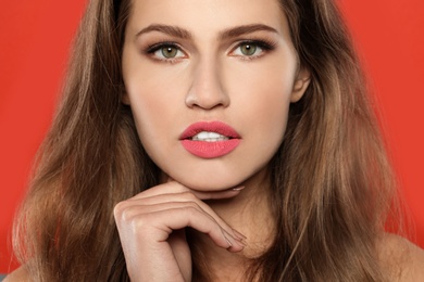 Photo of Young woman wearing beautiful lipstick on color background