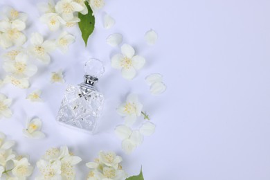 Photo of Aromatic perfume in bottle and beautiful jasmine flowers on white background, flat lay. Space for text