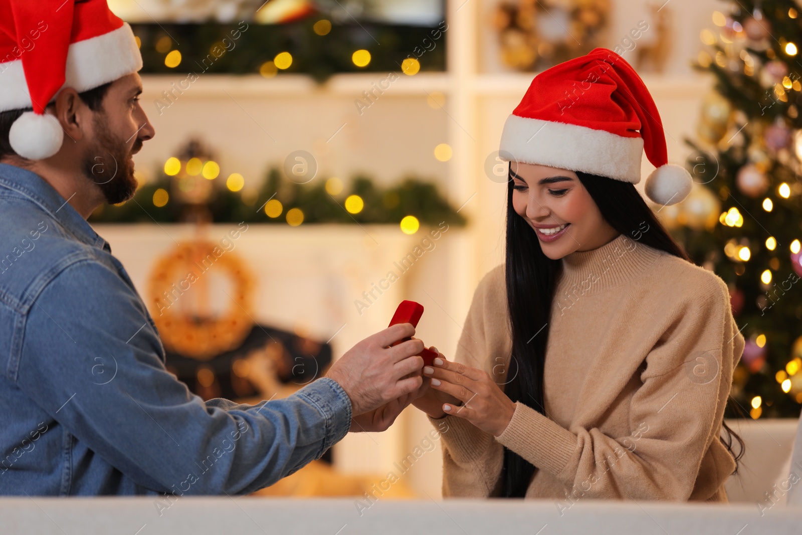 Photo of Man with engagement ring making proposal to his girlfriend at home on Christmas