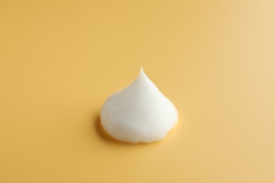 Photo of Sample of face cream on yellow background
