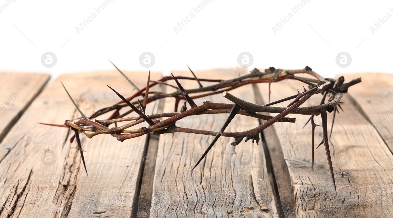 Photo of Crown of thorns on wooden table against white background, space for text. Easter attribute