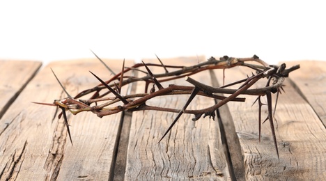 Photo of Crown of thorns on wooden table against white background, space for text. Easter attribute