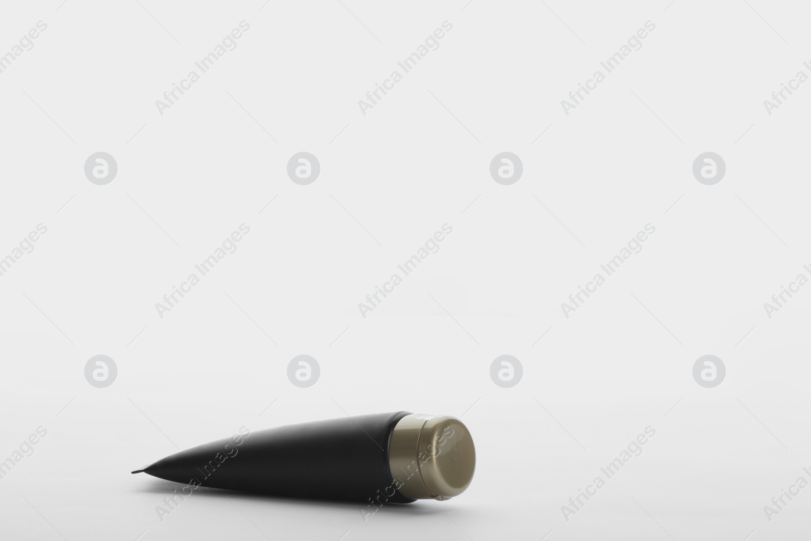 Photo of Black tube against white background. Cosmetic product for men