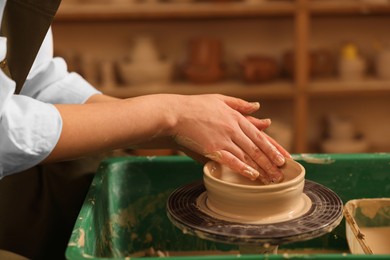 Photo of Clay crafting. Woman making bowl on potter's wheel in workshop, closeup