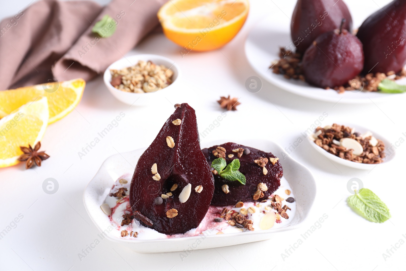 Photo of Tasty red wine poached pears with muesli and yoghurt in bowl on white table