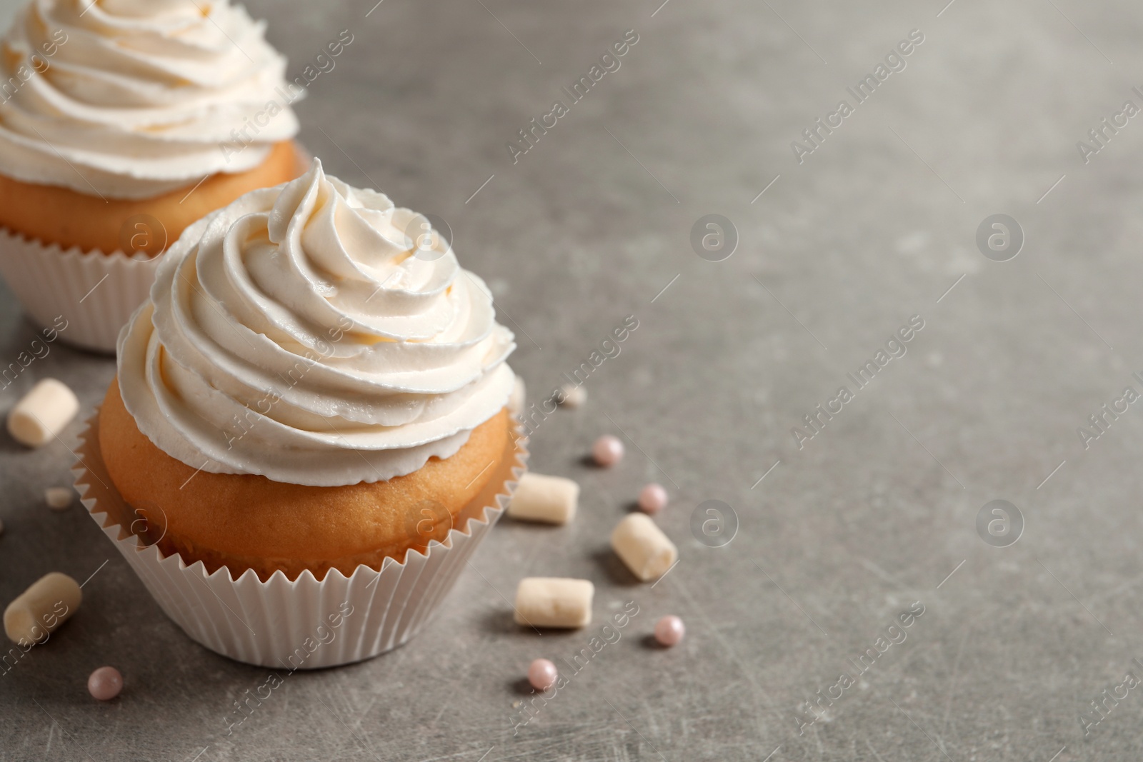 Photo of Delicious cupcakes decorated with cream on light grey table. Space for text