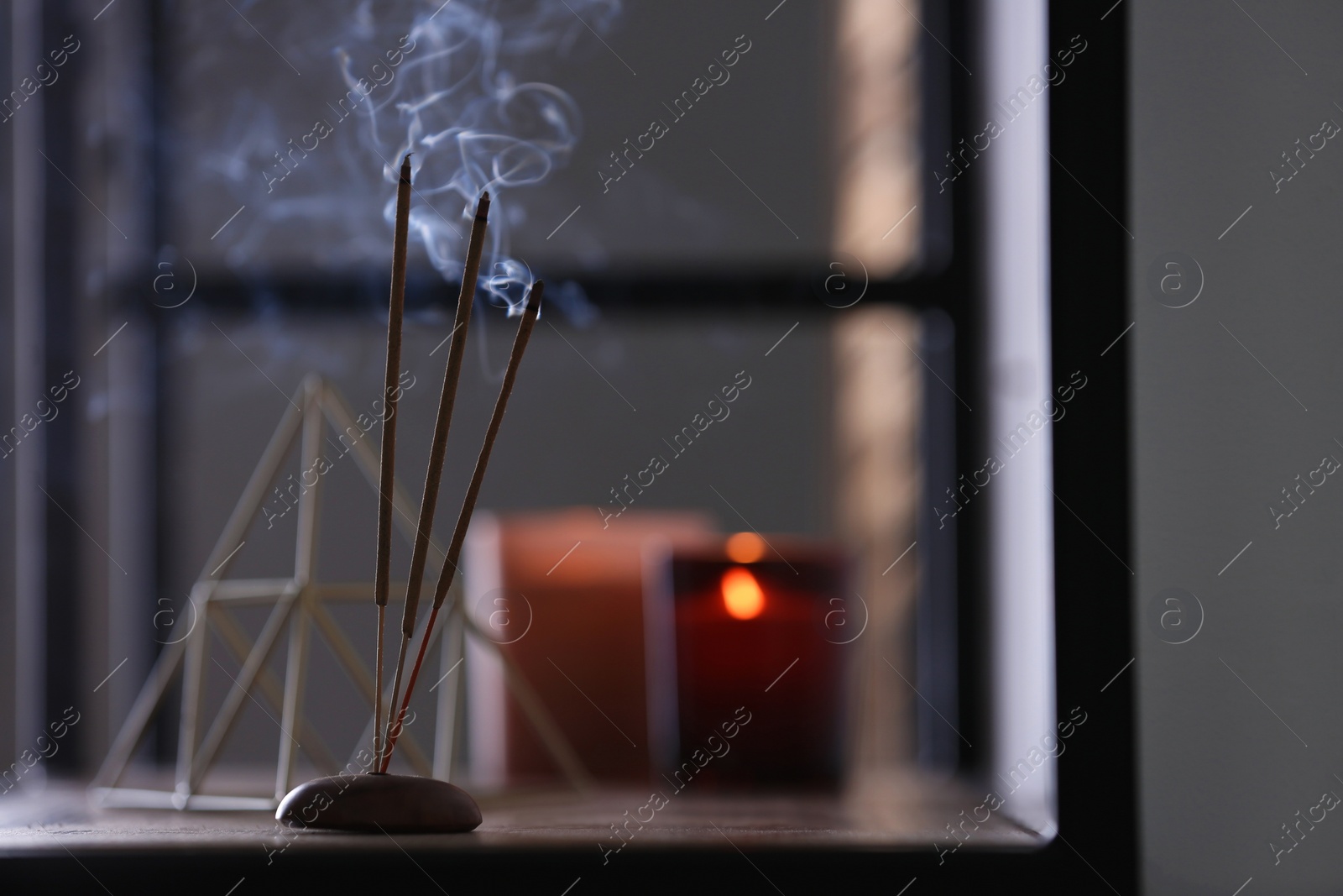 Photo of Incense sticks smoldering on shelf indoors, space for text