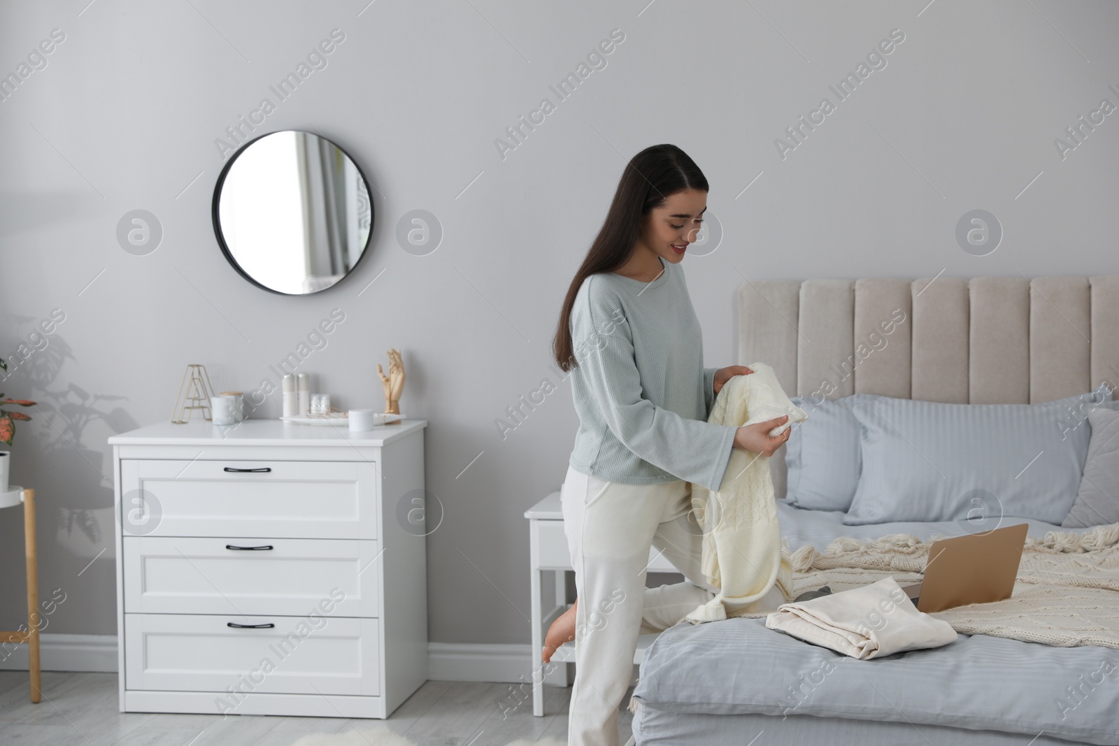 Photo of Young woman choosing clothes for work day at home. Morning routine