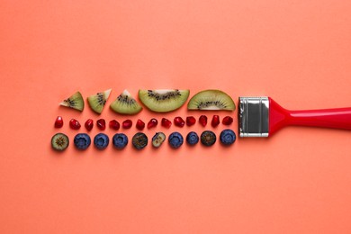Photo of Creative flat lay composition with paint brush, fruits and berries on coral background