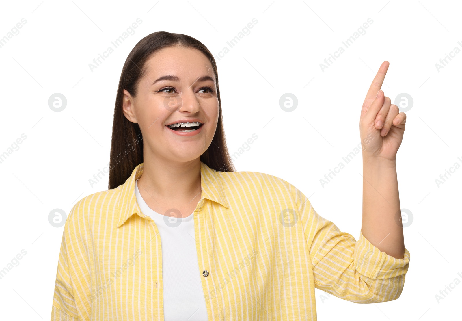 Photo of Smiling woman with dental braces pointing at something on white background