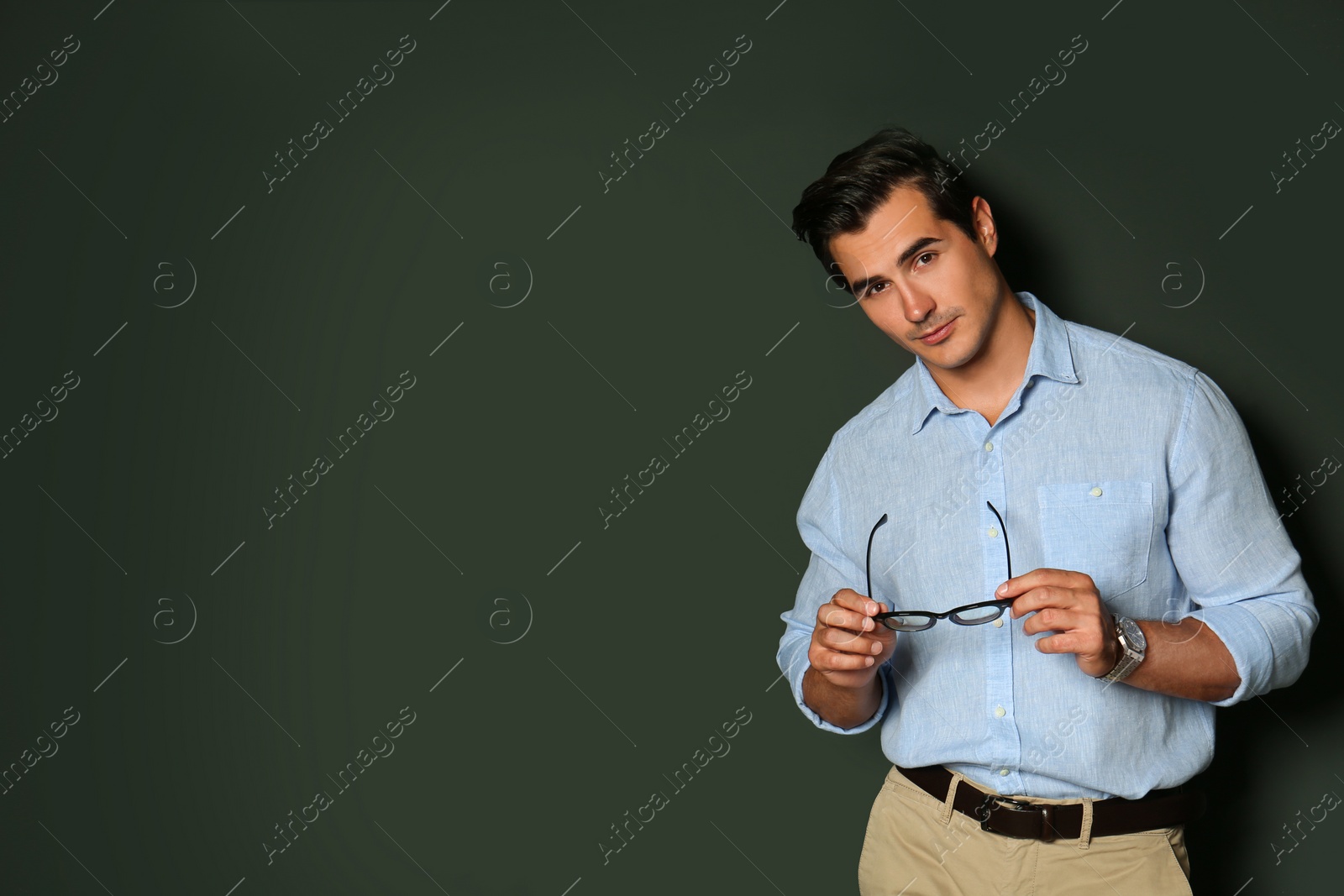 Photo of Handsome young man in stylish clothes with glasses on dark background. Space for text