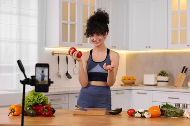 Smiling food blogger explaining something while recording video in kitchen