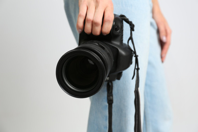 Professional photographer with modern camera on light background in studio, closeup