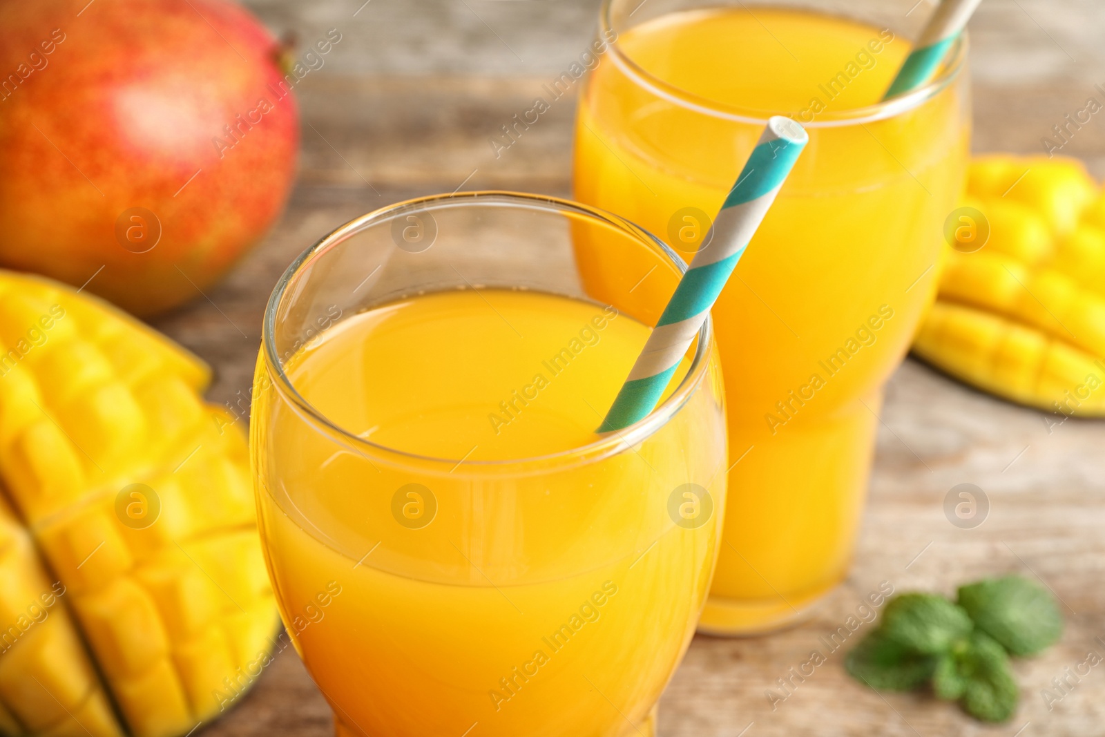 Photo of Fresh tropical mango juice on wooden table, closeup