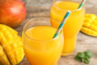 Fresh tropical mango juice on wooden table, closeup